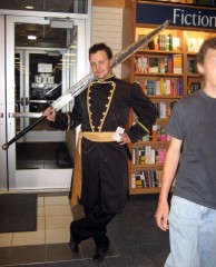 Rubix dressed as Wit holding Brandon's assistant's sword.